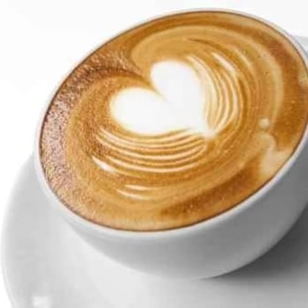 Close-up of a latte in a white cup with a heart design in the foam.