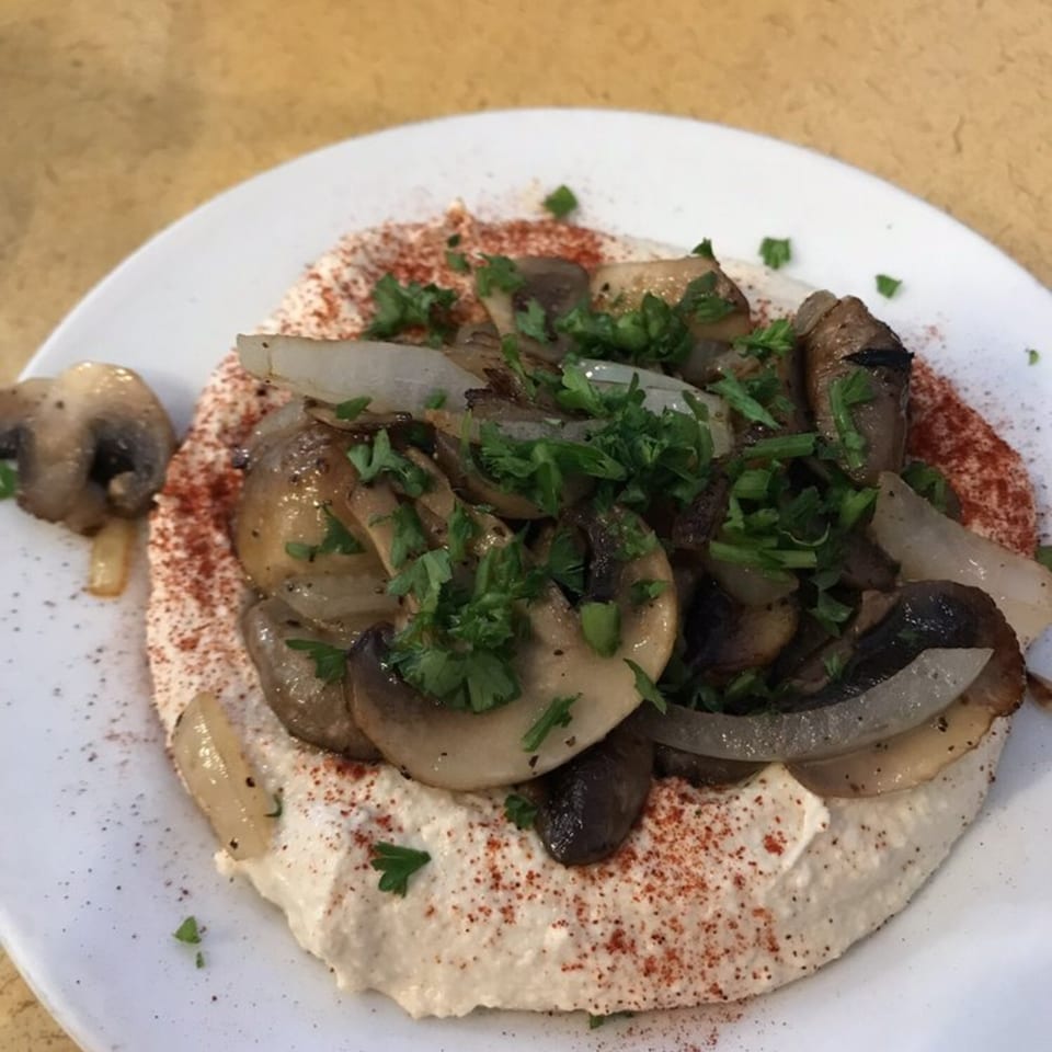 Hummus topped with sautéed mushrooms, onions, and fresh parsley, sprinkled with paprika.